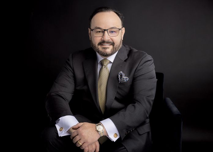 Dr. Aldo Guerra in black suit with tan tie and blue handkerchief